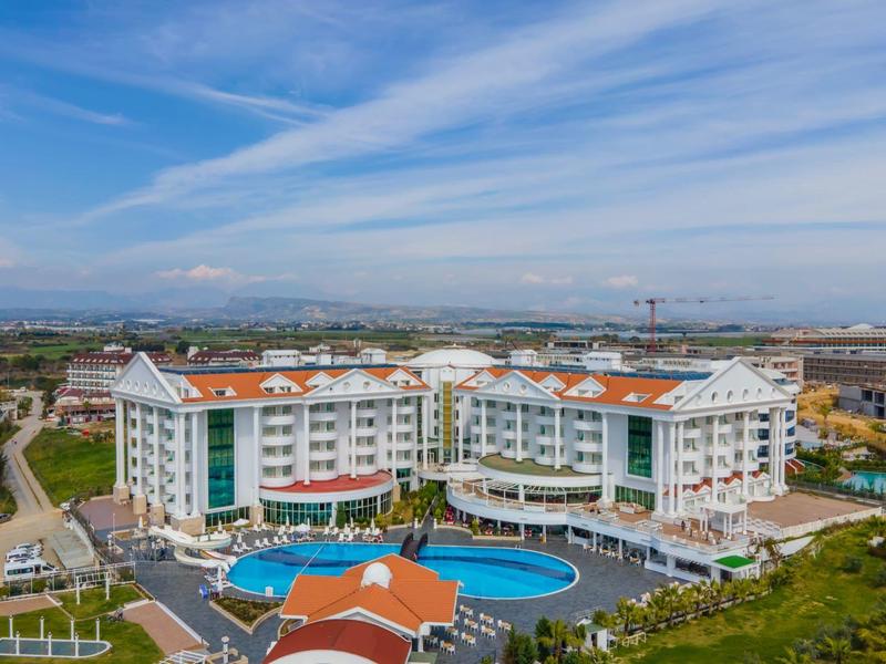 Grande hotel con piscina, circondato da spazi verdi e ampio panorama sul cielo.