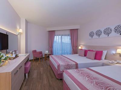 Nowoczesny pokój hotelowy z dwoma łóżkami, różowymi akcentami i telewizorem.