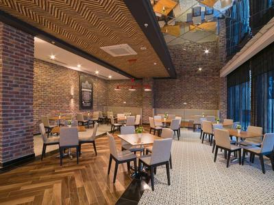 Nowoczesna restauracja z drewnianymi podłogami, ścianami z cegły oraz wygodnymi stołami i krzesłami.