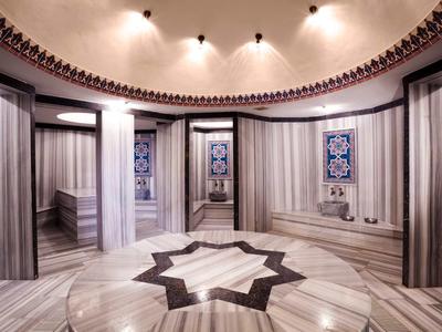 Eleganckie okrągłe pomieszczenie z marmurowymi ścianami, kolumnami i wzorem gwiazdy na podłodze.