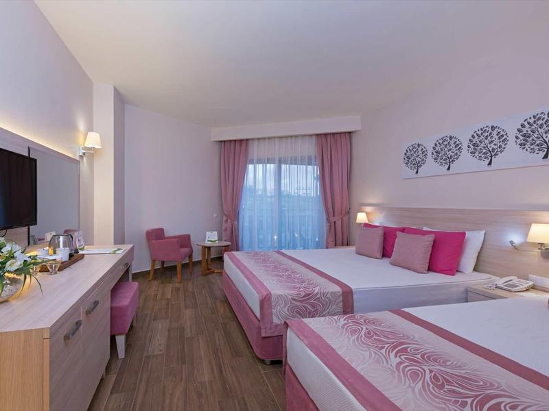 Nowoczesny pokój hotelowy z dwoma łóżkami, różowymi akcentami i telewizorem.