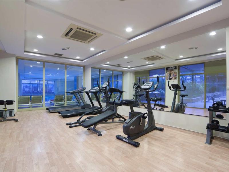 Nowoczesna siłownia z bieżniami, rowerami i hantlami, duże okna z widokiem.