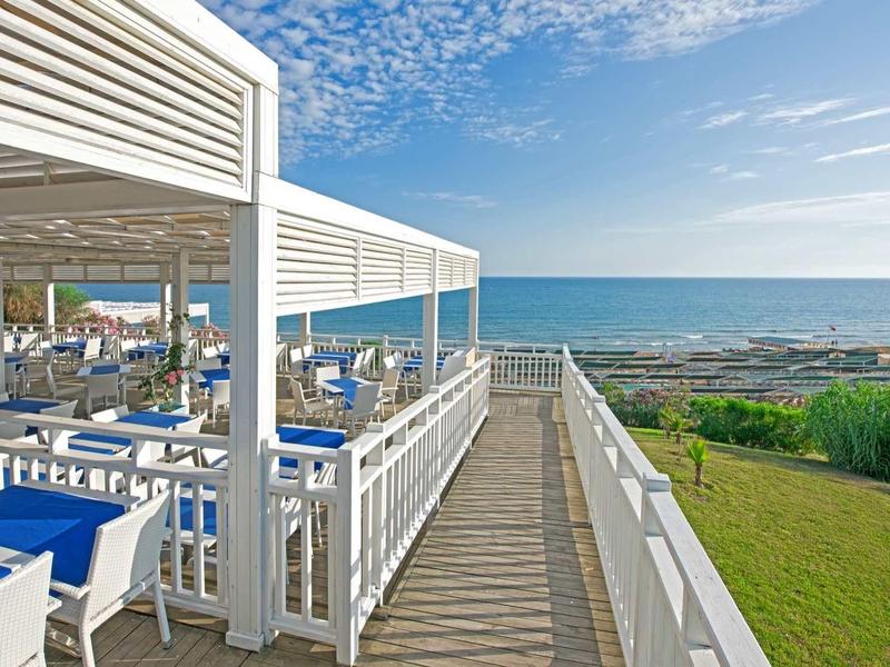 Restauracja przy plaży z widokiem na morze, zadaszone miejsca i niebieskie niebo.