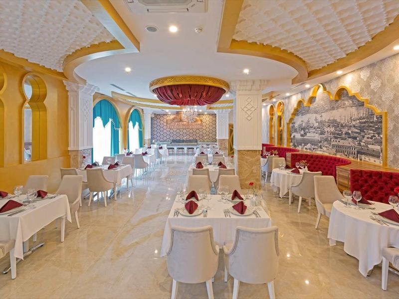 Elegancka, jasna restauracja z białymi stołami i żółtymi ścianami ozdobionymi obrazami.