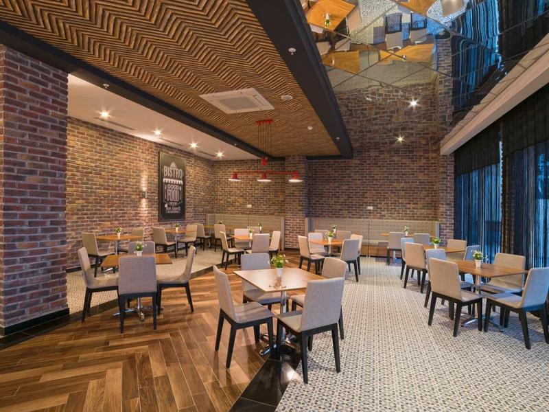 Nowoczesna restauracja z drewnianymi podłogami, ścianami z cegły oraz wygodnymi stołami i krzesłami.