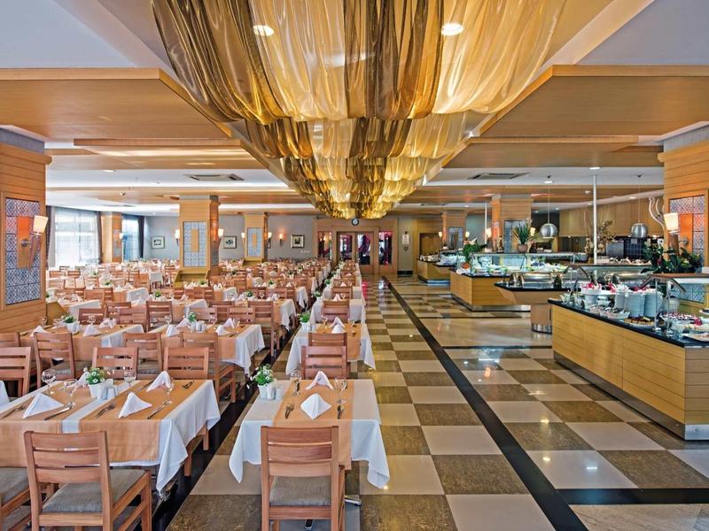 Duża, jasna restauracja z białymi obrusami i bufetem.