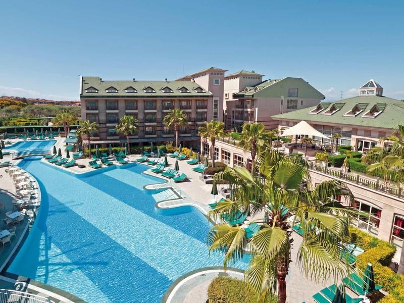 Duży basen hotelowy z leżakami i otaczającym budynkiem hotelu pod czystym niebem.