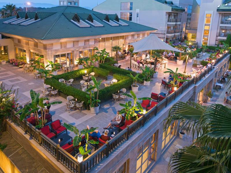 Wieczorny widok oświetlonej restauracji hotelowej z ogrodem i tarasem na dachu.