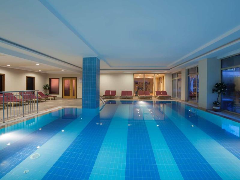 Basen wewnętrzny z niebieskimi płytkami i miejscem do siedzenia w nowoczesnym hotelu.