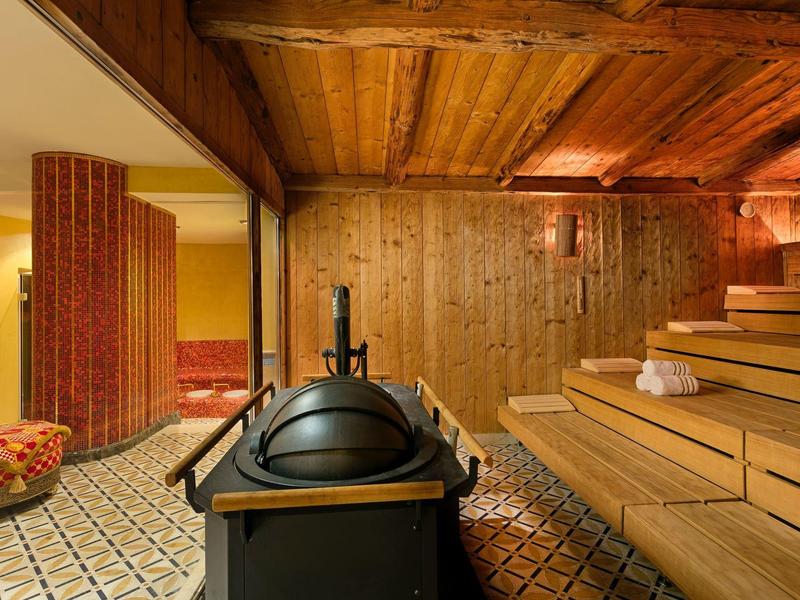 Drewniana sauna z tradycyjnym piecem i pochylonymi ławkami w ciepłej atmosferze.