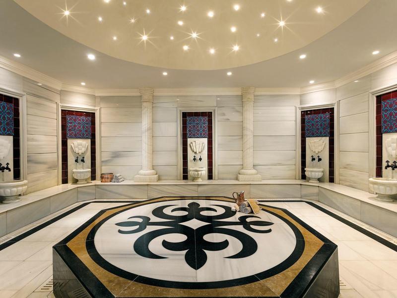 Luksusowe wnętrze hammamu z ozdobną podłogą i gwiaździstym oświetleniem sufitowym.