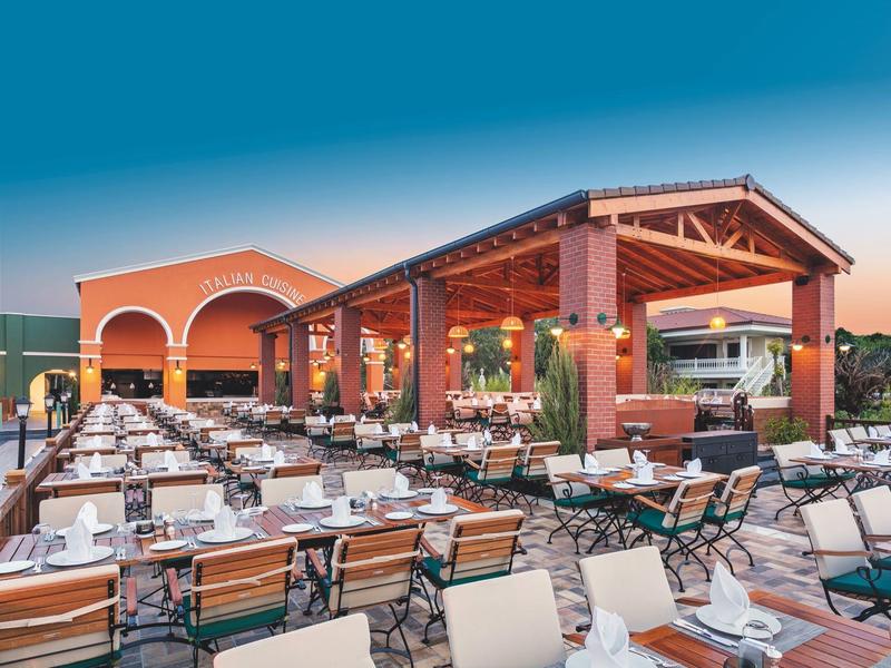 Otwarta restauracyjna przestrzeń z stołami i krzesłami pod niebieskim niebem.