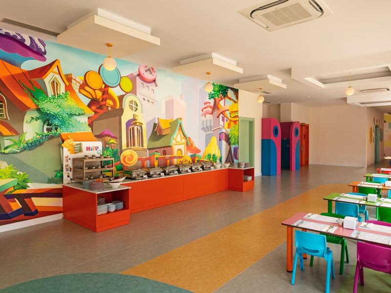 Kolorowy kącik zabaw ze stołami i krzesłami w sali rekreacyjnej hotelu.