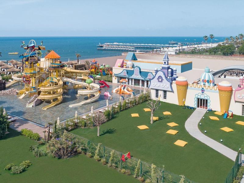 Kolorowy park wodny z zjeżdżalniami i budynkami przy plaży i morzu.