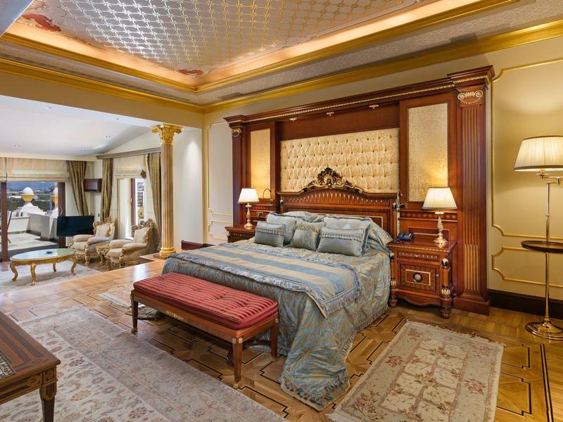 Luksusowy pokój hotelowy z dużym łóżkiem, meblami z drewna i dekoracyjnym dywanem.