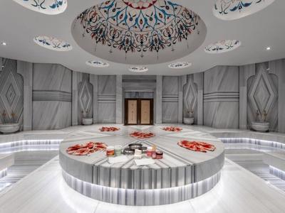 Nowoczesny hammam z okrągłą marmurową fontanną i ozdobnym malowidłem sufitowym.