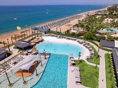 Luksusowy basen hotelowy z parasolami i bezpośrednim dostępem do piaszczystej plaży i morza.