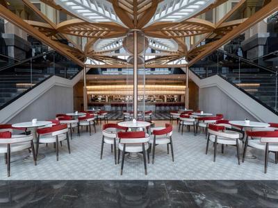 Elegancka restauracja hotelowa z nowoczesnymi krzesłami, czerwonymi obrusami i odkrytym drewnianym sufitem.