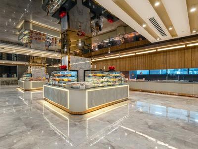 Nowoczesny hotel z jasną marmurową podłogą i oświetlonym centralnym biurkiem recepcyjnym.