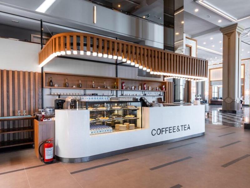Nowoczesne stoisko z kawą i herbatą z drewnianymi elementami w jasnym hotelu.