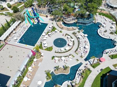 Widok z lotu ptaka na basen hotelowy z kilkoma basenami, zjeżdżalniami i leżakami.