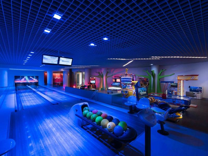 Modern bowling alley with glowing blue lights, lanes, bowling balls, and digital scoreboards.