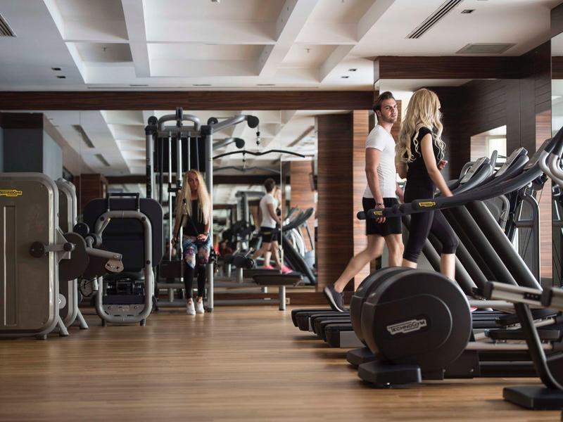 Modern gym with treadmills and fitness machines, two people exercising in a hotel gym.