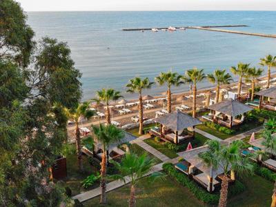 Vista su un giardino dell'hotel con palme e padiglioni vicino al mare.