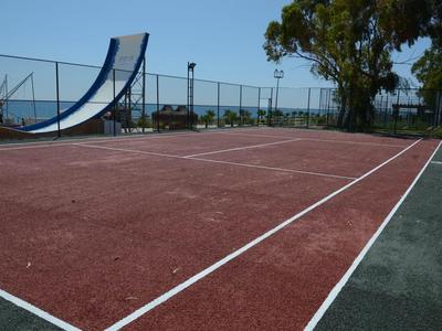 Campo da tennis vuoto con superficie rossa e verde sotto un cielo azzurro