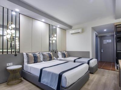 Moderní hotelový pokoj se dvěma jednolůžky, stylovými polštáři a jemným osvětlením.