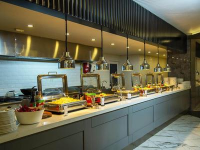 Moderní hotelová kuchyně s bufetem a různými pokrmy pod závěsnými světly.