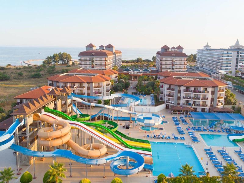 Velký hotel s několika tobogány a bazénem blízko pláže.