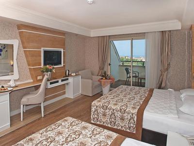 Modernes Hotelzimmer mit zwei Betten, Schreibtisch, Fernseher und Balkon mit Meeresblick.