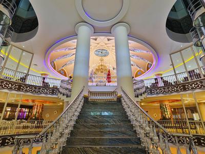 Gran escalinata central con columnas y ventanas en un lujoso vestíbulo de hotel