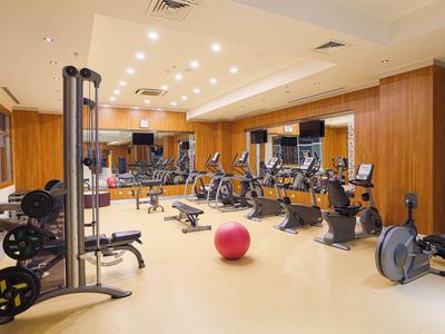 Gimnasio luminoso con equipos, pesas y una pelota de ejercicios rosa.