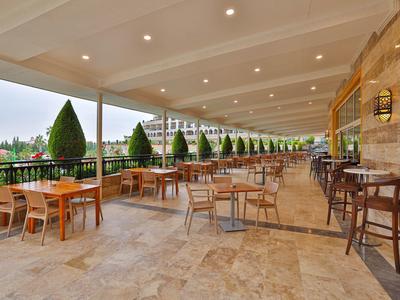 Terraza abierta de un hotel con mesas, sillas y vista a plantas verdes.