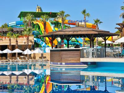 Área de piscina con toboganes de agua, tumbonas y sombrillas en un resort tropical.