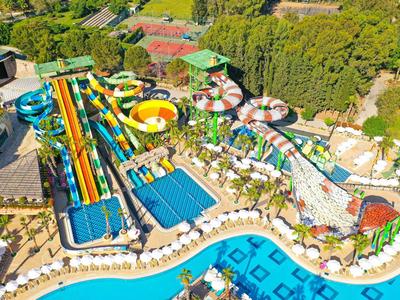 Parque acuático colorido con toboganes, piscinas y sombrillas en un resort tropical.