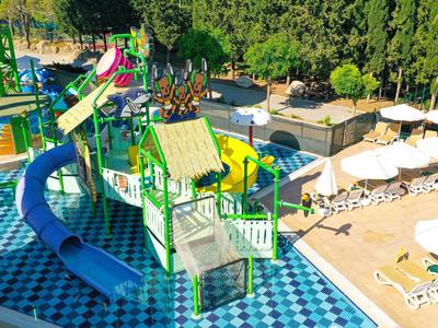 Área de juegos acuáticos con toboganes y sombrillas junto a una piscina en un complejo vacacional