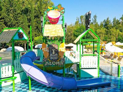 Parque acuático colorido con toboganes y techos verdes al aire libre bajo el sol.