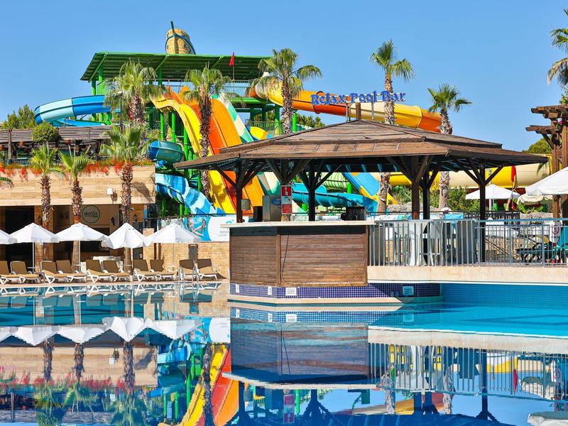 Área de piscina con toboganes de agua, tumbonas y sombrillas en un resort tropical.