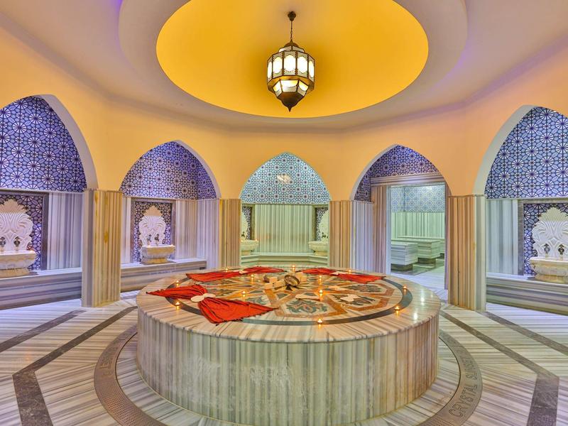 Hamam turco lujoso con lavabo de mármol central y ventanas arqueadas decorativas.