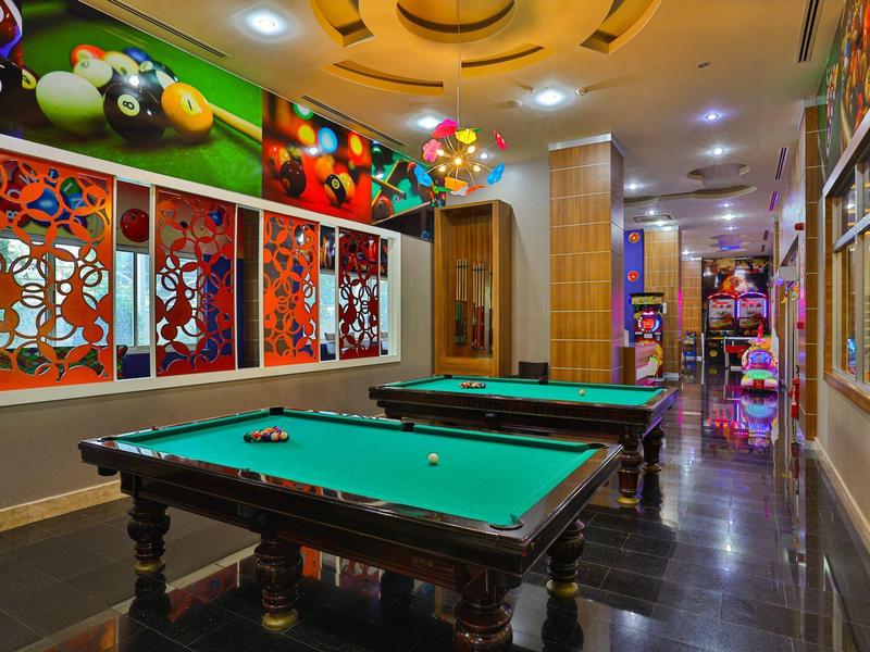 Sala de billar con dos mesas y decoración colorida en un área de hotel moderna.