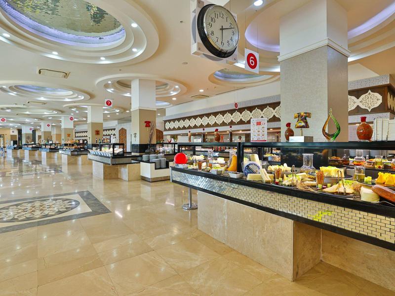 Amplia zona de buffet con variedad de alimentos y suelo de mármol claro en un hotel.