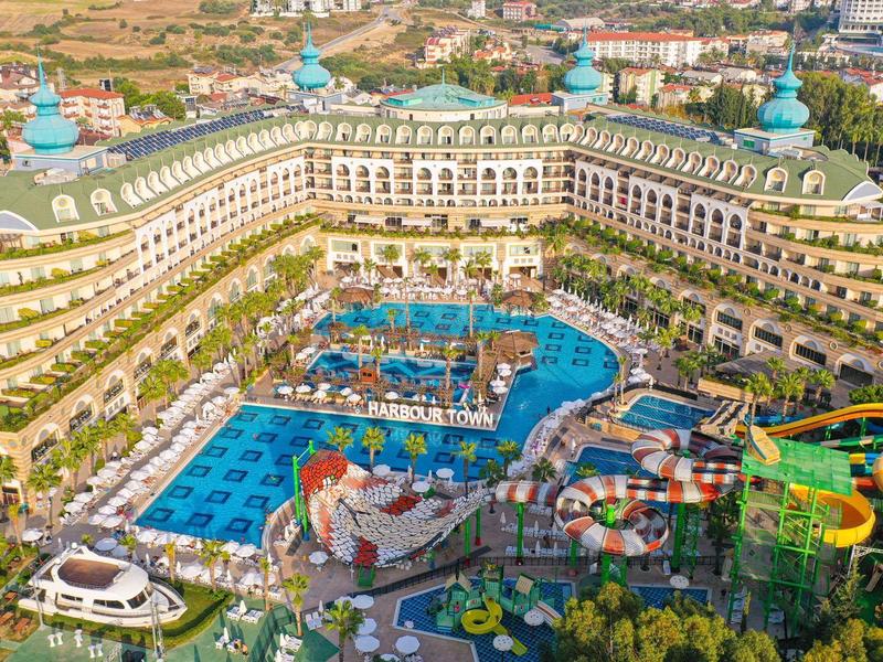 Resort de lujo con varias piscinas, toboganes de agua y terrazas verdes en paisaje soleado.