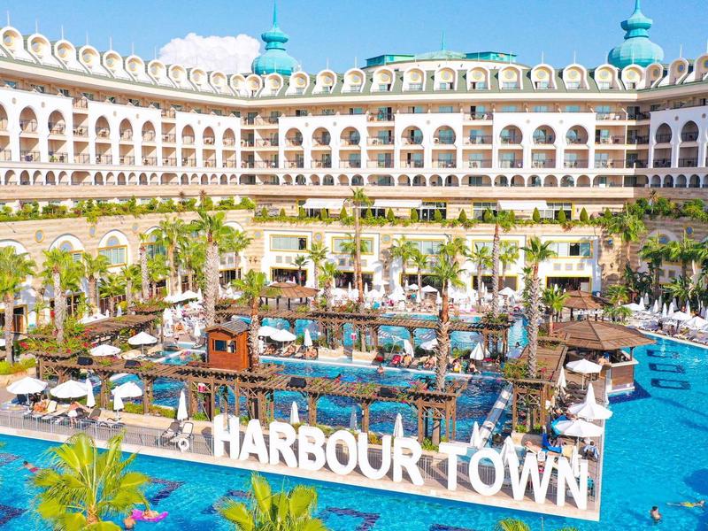 Gran piscina del hotel con palmeras y tumbonas en un edificio semicircular con balcones.