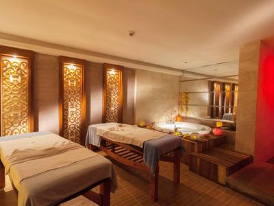 Przytulny pokój spa z ozdobnymi drewnianymi panelami i dwoma stołami do masażu.