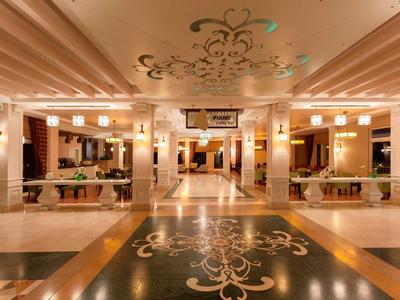 Elegancka lobby hotelowa z ciepłym oświetleniem, ozdobnymi podłogami i stylowymi miejscami do siedzenia.