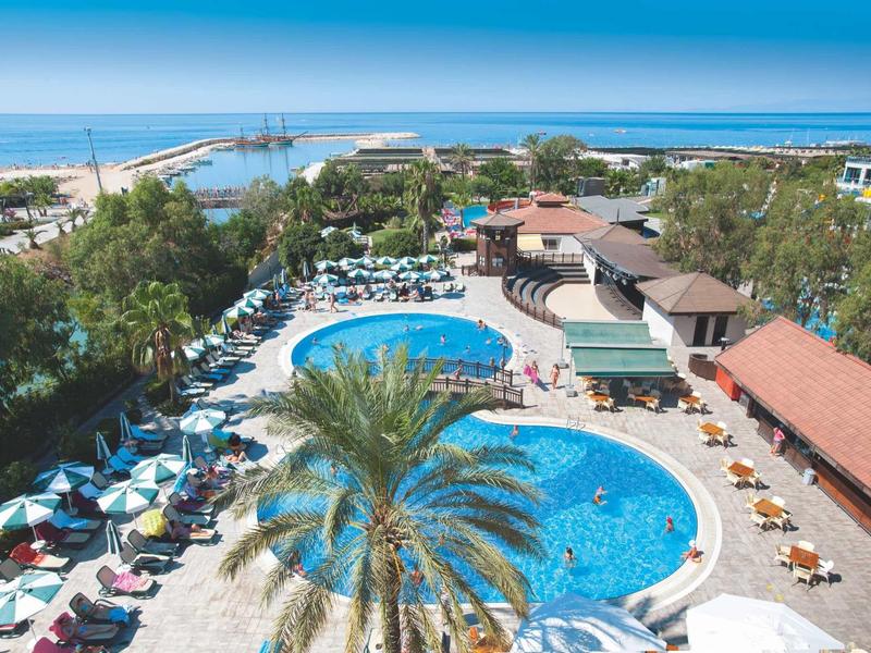 Hotel z dużymi basenami, parasolami i widokiem na morze.