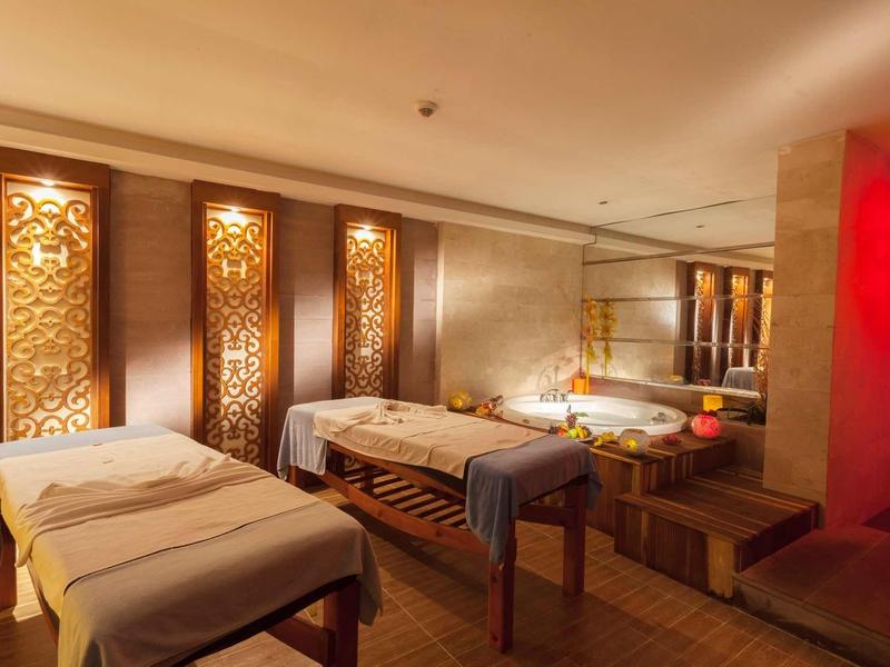 Przytulny pokój spa z ozdobnymi drewnianymi panelami i dwoma stołami do masażu.